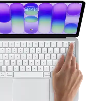 MacBook Neo, Farbe Silber, Anmeldebildschirm, ein Finger berührt den Touch ID Sensor oben rechts auf der Tastatur